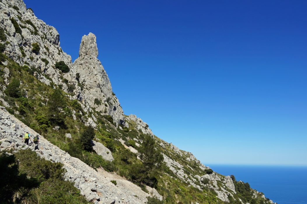 Walkers cross steep boulder scree on the rugged slopes of Galatzó