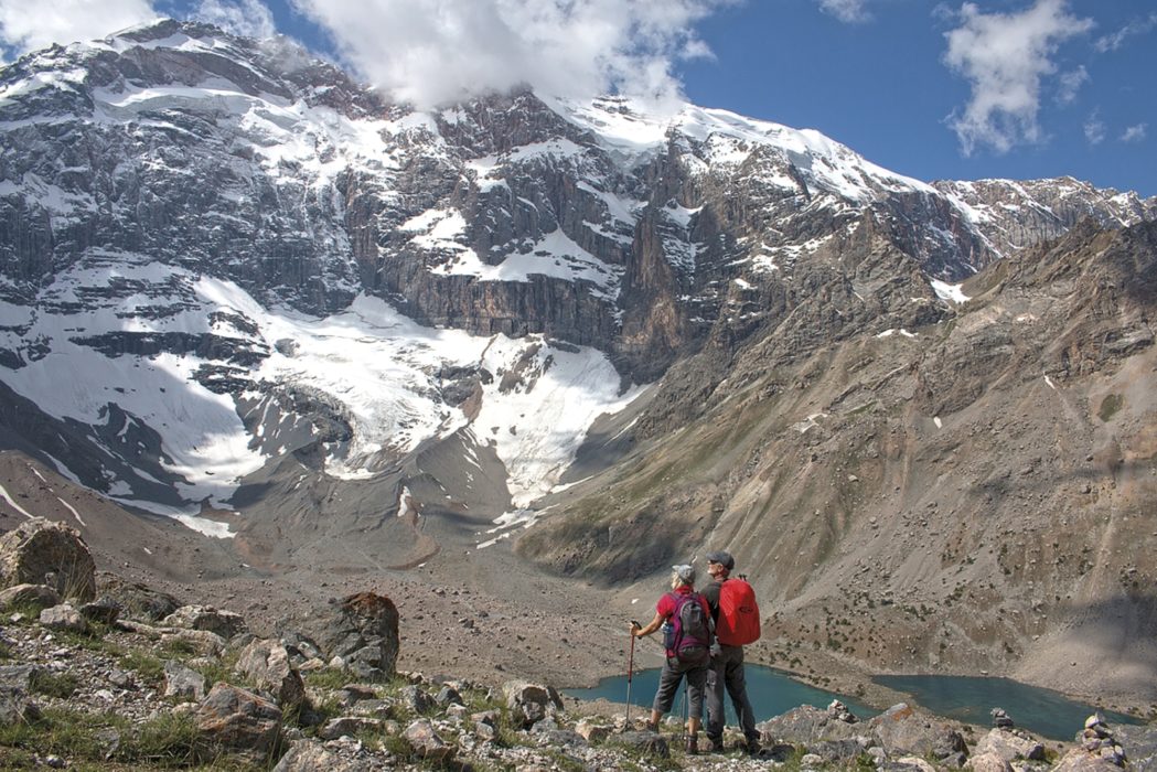 Trekkers enjoy the scenery, looking up the huge north face of Mirali Peak