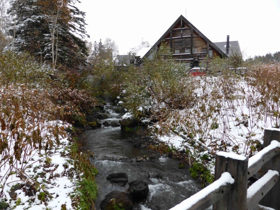 A Mountain Hut Next To A Steaming Thermal River In Daisetsuzan